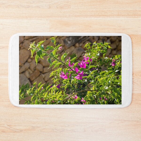 Item preview, Sunlit Pink Bougainvillea Blossoms Against Rustic Stone Wall With Lush Green Leaves Outdoor Garden Branches designed and sold by Nmallia.