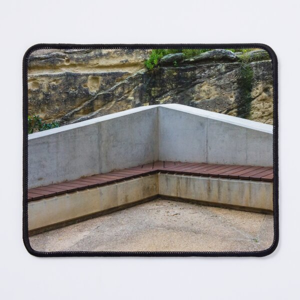 Item preview, Concrete Corner Bench With Wooden Slats Against Weathered Rock Wall In Outdoor Park designed and sold by Nmallia.