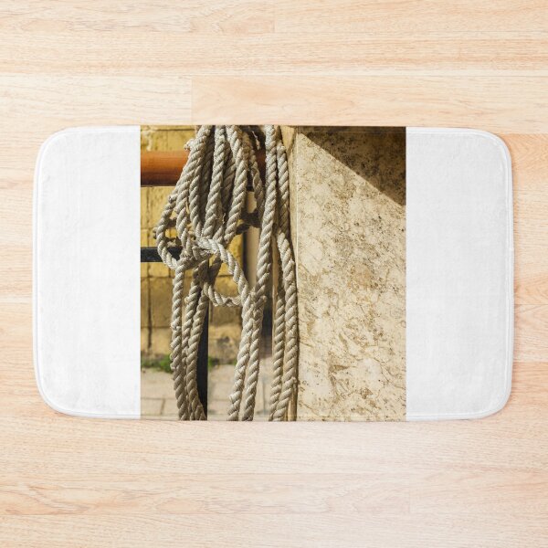 Item preview, Coiled Rope Hanging on Stone Railing Beside Marble Wall with Sunlit Texture and Shadows designed and sold by Nmallia.
