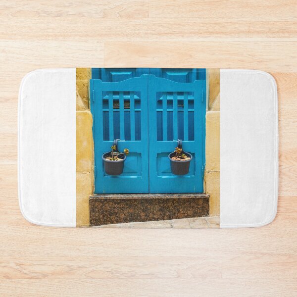 Item preview, Bright Blue Door With Hanging Plant Pots Against Sunlit Yellow Stone Wall In Mediterranean Street designed and sold by Nmallia.