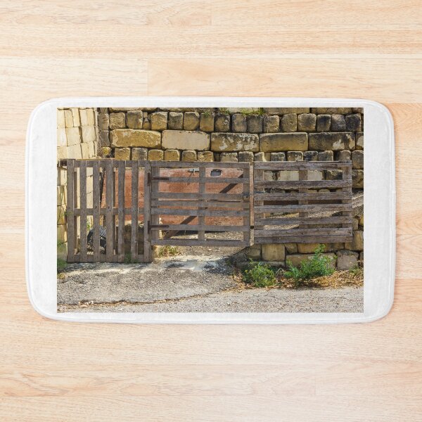 Item preview, Rustic Wooden Gate and Pallet Fence Against Weathered Stone Wall in Rural Farmyard Entrance designed and sold by Nmallia.
