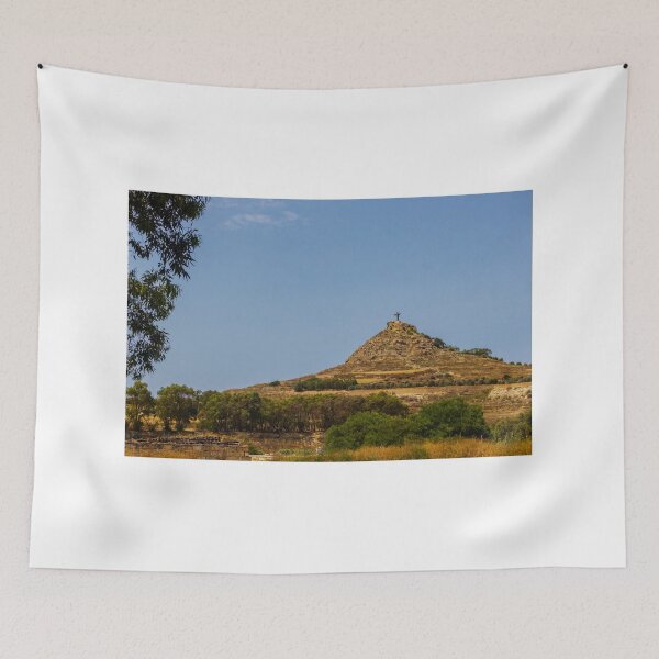 Item preview, Cruz en la cima de una colina rocosa con vistas al paisaje rural bajo un cielo azul despejado. designed and sold by Nmallia.