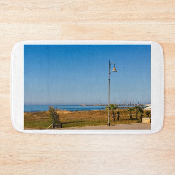 Item preview, Coastal Promenade Lamp Post Overlooking Calm Sea, Sandy Dunes and Distant Harbor Cranes at Sunrise designed and sold by Nmallia.