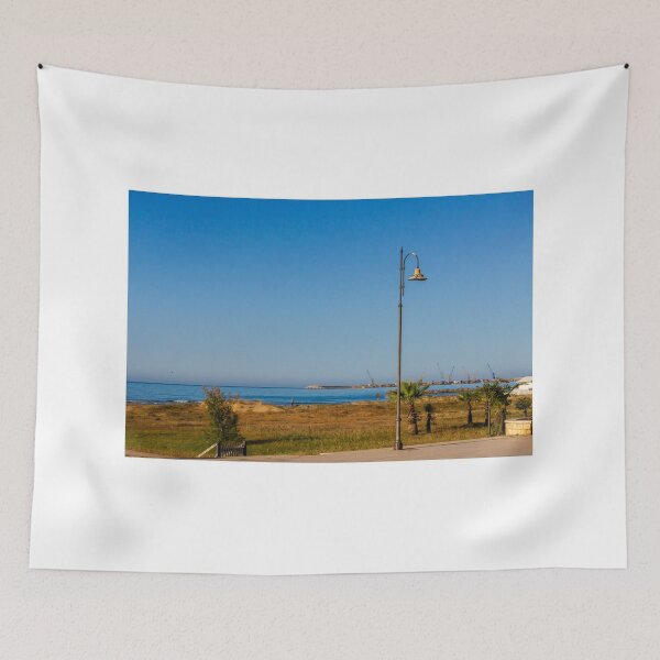 Item preview, Coastal Promenade Lamp Post Overlooking Calm Sea, Sandy Dunes and Distant Harbor Cranes at Sunrise designed and sold by Nmallia.