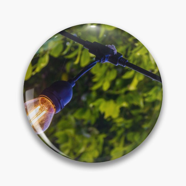Item preview, Warm Glowing Light Bulb Hanging From Outdoor String Lights Over Lush Green Garden Foliage designed and sold by Nmallia.