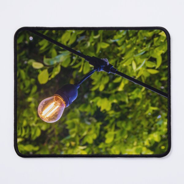Item preview, Warm Glowing Light Bulb Hanging From Outdoor String Lights Over Lush Green Garden Foliage designed and sold by Nmallia.