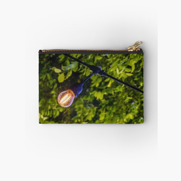 Item preview, Warm Glowing Light Bulb Hanging From Outdoor String Lights Over Lush Green Garden Foliage designed and sold by Nmallia.