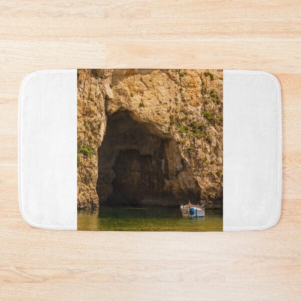 Item preview, Small Boat Anchored in Sea Grotto Beneath Sunlit Limestone Cliff With Green Water Reflections designed and sold by Nmallia.