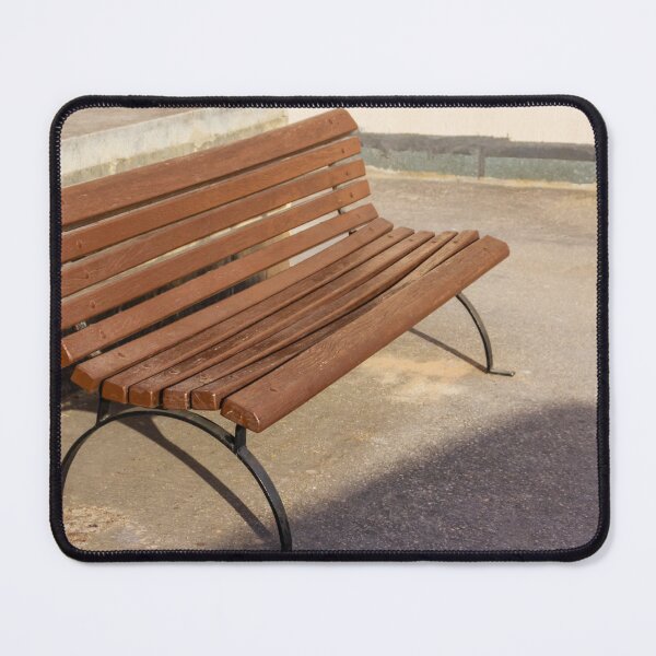Item preview, Empty Wooden Bench in Sunlit Urban Park Beside Stone Wall on Asphalt Walkway Outdoor Seating designed and sold by Nmallia.