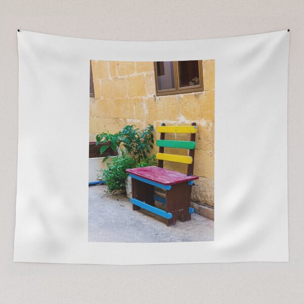 Item preview, Colorful Wooden Bench Against Textured Yellow Wall in Sunny Courtyard With Green Plants designed and sold by Nmallia.