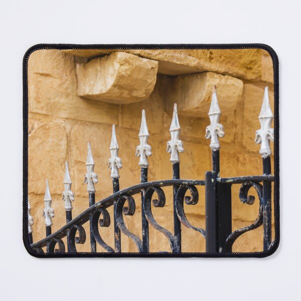 Item preview, Ornate Wrought Iron Fence With White Finials Against Warm Sandstone Wall In Historic Setting designed and sold by Nmallia.