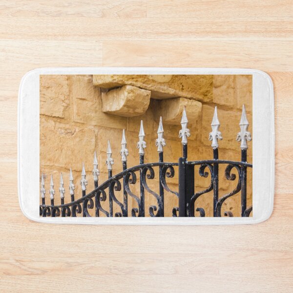 Item preview, Ornate Wrought Iron Fence With White Finials Against Warm Sandstone Wall In Historic Setting designed and sold by Nmallia.