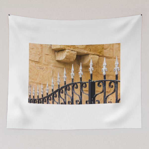 Item preview, Ornate Wrought Iron Fence With White Finials Against Warm Sandstone Wall In Historic Setting designed and sold by Nmallia.