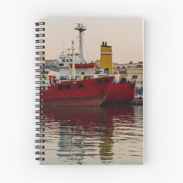 Item preview, Red Cargo Ship Docked at Industrial Harbor With Evening Reflections on Calm Water designed and sold by Nmallia.