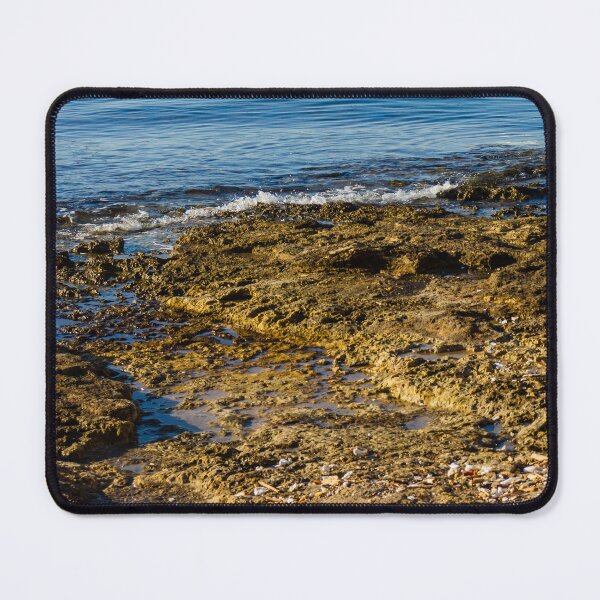 Item preview, Rugged Coastal Rocks By Calm Blue Water With Weathered Stone Pier And Small Post designed and sold by Nmallia.