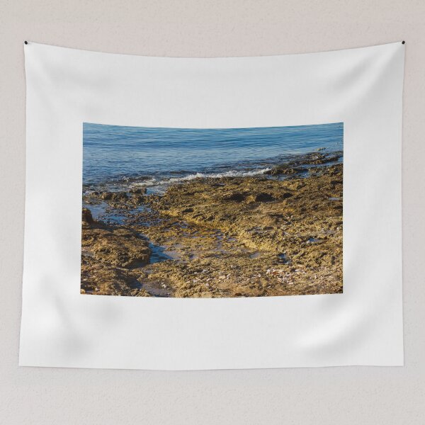 Item preview, Rugged Coastal Rocks By Calm Blue Water With Weathered Stone Pier And Small Post designed and sold by Nmallia.
