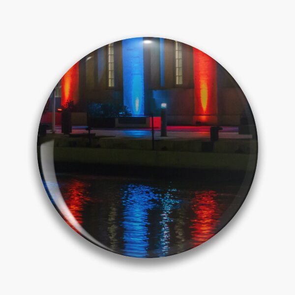 Item preview, Nighttime Waterfront Building With Red And Blue Illuminated Arches And Reflections On Water designed and sold by Nmallia.