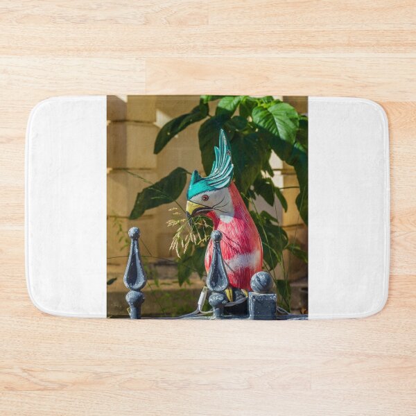 Item preview, Colorful Painted Bird Statue Perched on a Weathered Metal Fence Amid Lush Greenery designed and sold by Nmallia.