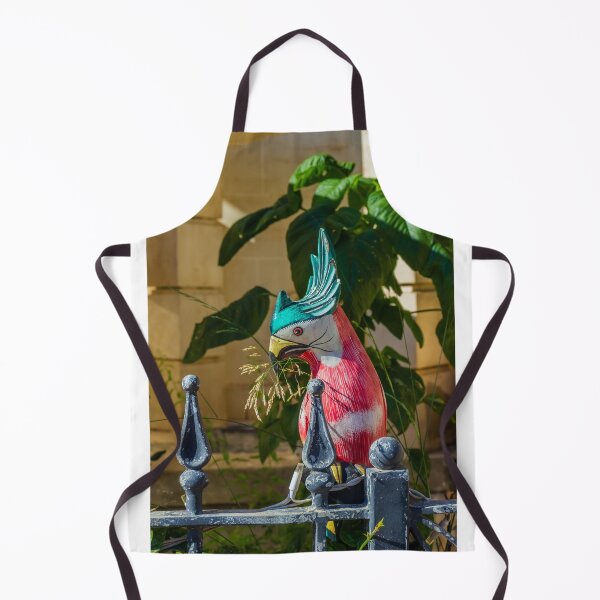 Item preview, Colorful Painted Bird Statue Perched on a Weathered Metal Fence Amid Lush Greenery designed and sold by Nmallia.