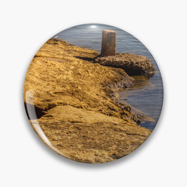 Item preview, Rugged Coastal Rocks By Calm Blue Water With Weathered Stone Pier And Small Post designed and sold by Nmallia.