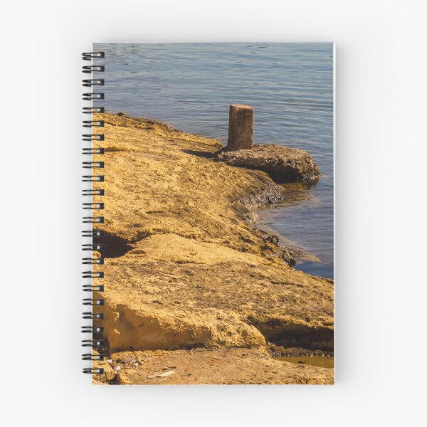 Item preview, Rugged Coastal Rocks By Calm Blue Water With Weathered Stone Pier And Small Post designed and sold by Nmallia.