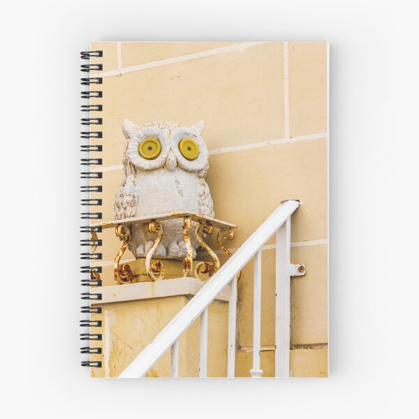 Item preview, Whimsical Stone Owl Statue With Yellow Eyes Guarding Rusty Railing Above Beige Wall designed and sold by Nmallia.