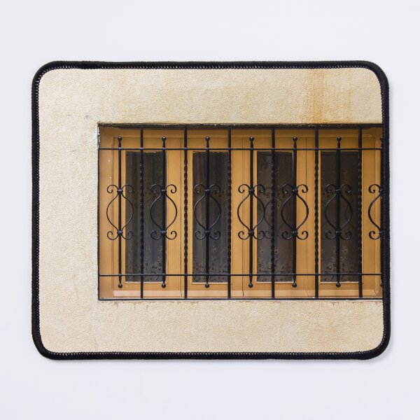 Item preview, Yellow Wall With Decorative Iron Window Bars Guarding A Beige Facade On A Quiet Street Scene designed and sold by Nmallia.
