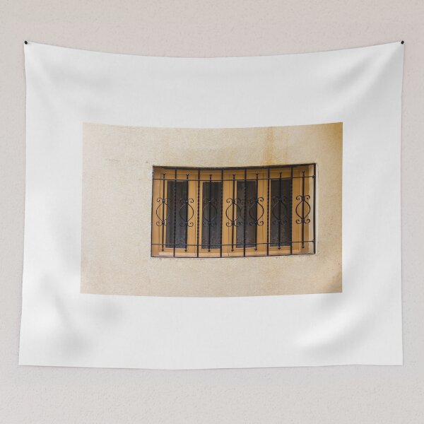 Item preview, Yellow Wall With Decorative Iron Window Bars Guarding A Beige Facade On A Quiet Street Scene designed and sold by Nmallia.