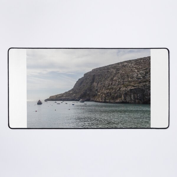 Item preview, Boats Anchored in a Quiet Rocky Bay Beneath a Dramatic Cliffside Under Overcast Sky designed and sold by Nmallia.