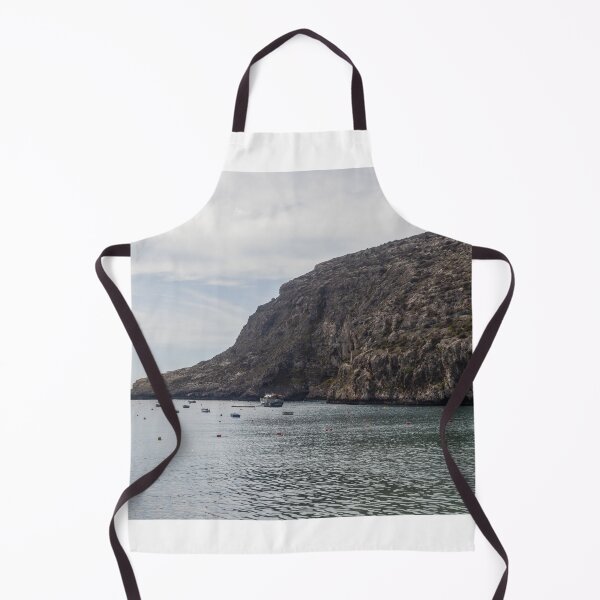 Item preview, Boats Anchored in a Quiet Rocky Bay Beneath a Dramatic Cliffside Under Overcast Sky designed and sold by Nmallia.