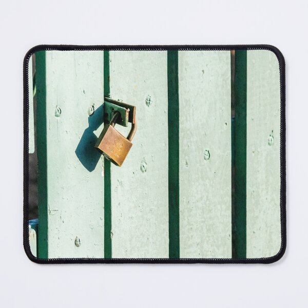 Item preview, Rustic Brass Padlock Securing Pale Green Wooden Fence Panel Casting Shadow in Sunlight designed and sold by Nmallia.