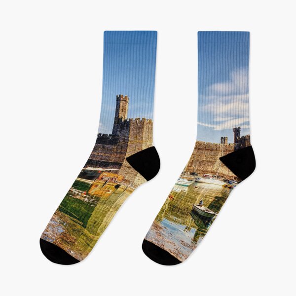Item preview, Caernarfon Castle reflected in the tranquil waters of its harbour, with a historic vessel moored beneath the imposing medieval fortress.  designed and sold by Kevin Hellon.