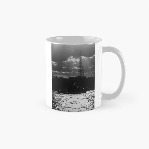 Item preview, Silhouette Tugboat at Sunset With Industrial Tower and Dramatic Sun Rays Over Water designed and sold by Nmallia.