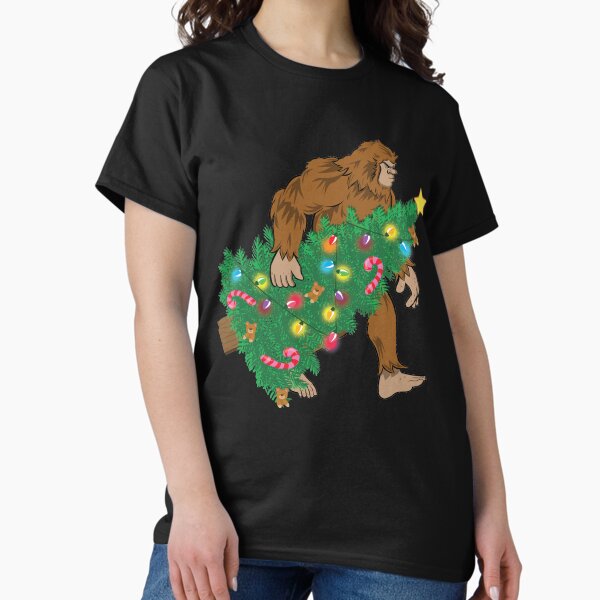 Item preview, Funny Sasquatch Carrying Christmas Tree Bigfoot Holiday Shirt designed and sold by tronictees.