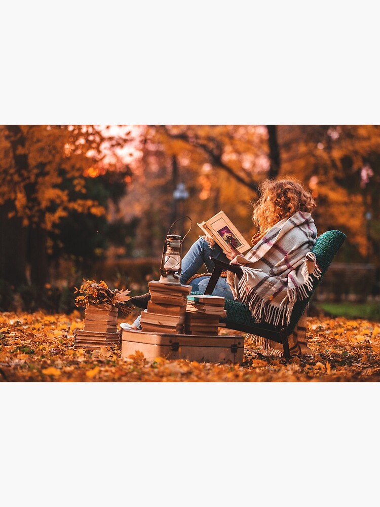 Beautiful girl in autumn forest reading a book covered with a warm